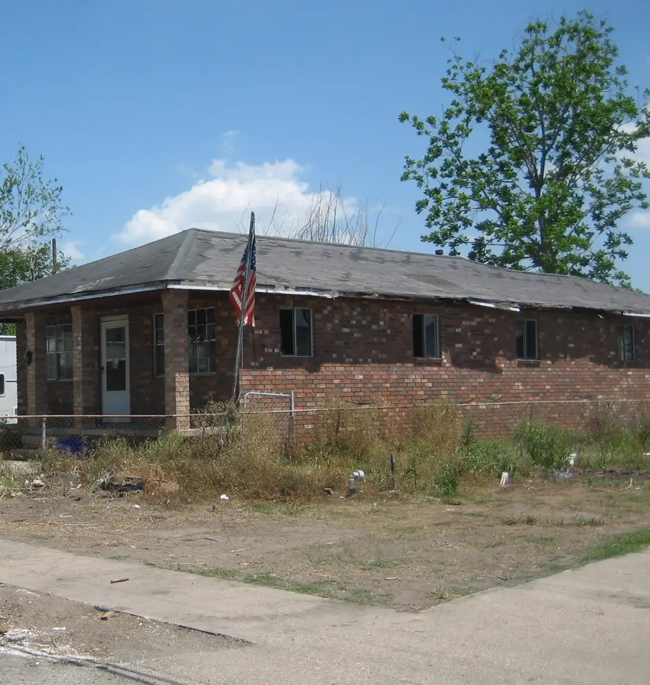Dated single-story brick ranch house on a slab with an overgrown yard